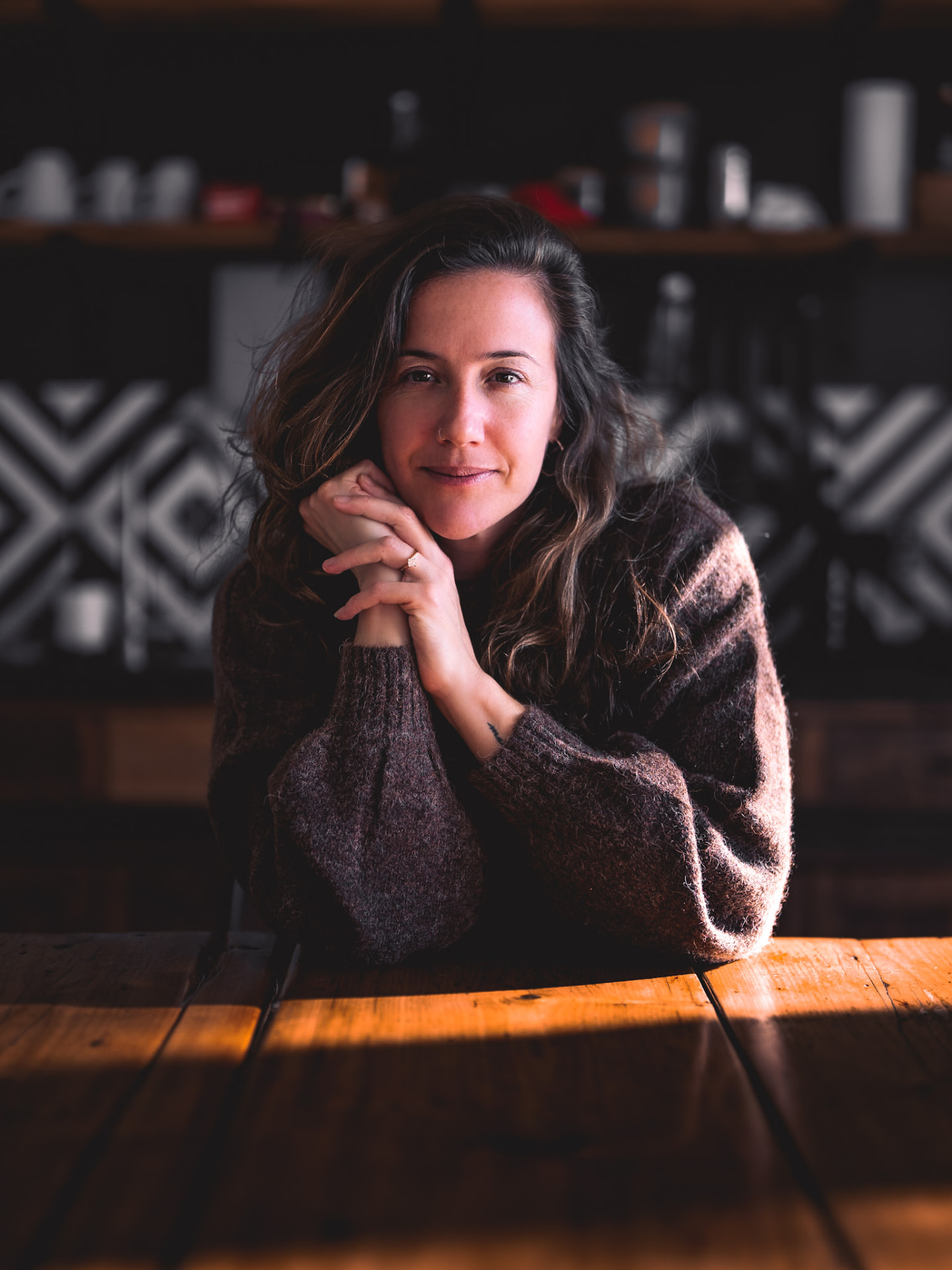Fiona Dixon resting her chin on her hands at a warmly lit timber table in a cafe